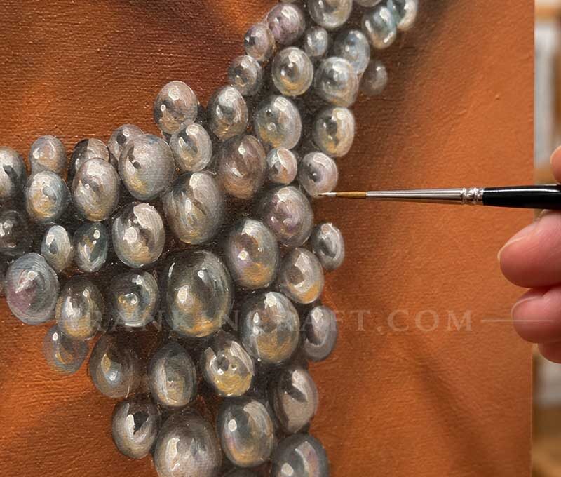 Close-up of an artist using a fine brush to paint intricate details and reflections on realistic pearls.