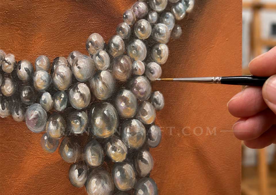 Close-up of an artist using a fine brush to paint intricate details and reflections on realistic pearls.