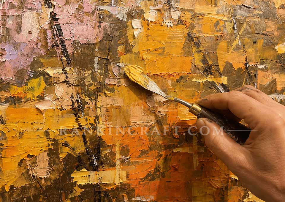 Close-up of an artist applying thick golden paint with a palette knife to the textured Golden Canopy artwork.